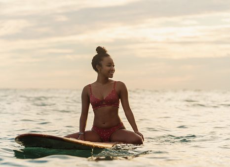 young woman sitting on her surfboard waiting for a wave. hawaii 2019